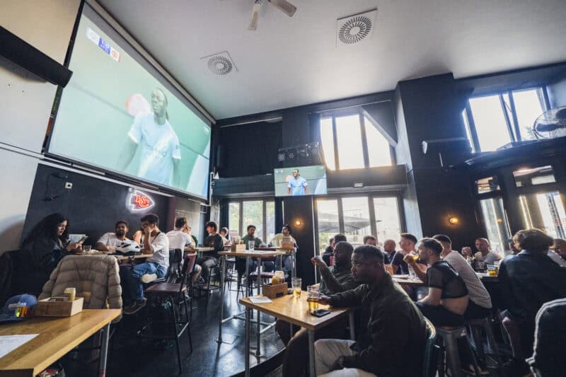 Bright interior with high ceilings and large windows, creating a lively social atmosphere.