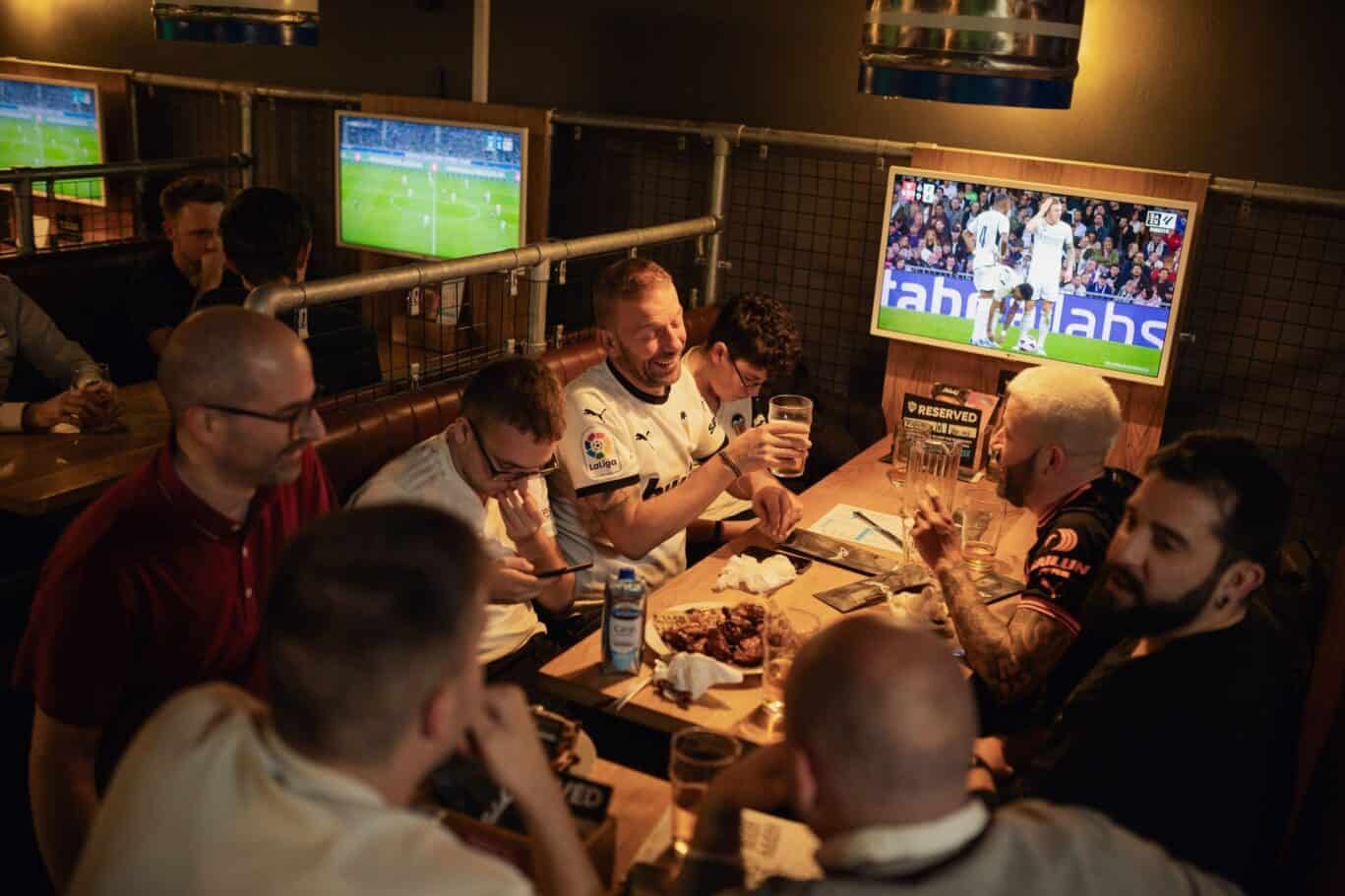 Group of friends watching a football match at Alexanderplatz hostel bar.