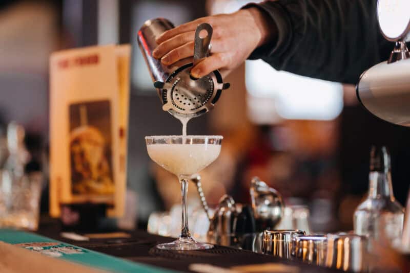 Bartender pouring cocktail at Alexanderplatz Hostel bar in Berlin.