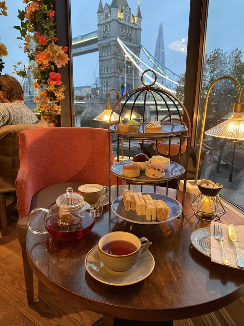 Charming tea setup featuring cakes and tea with a scenic view of Tower Bridge in London. Perfect for.