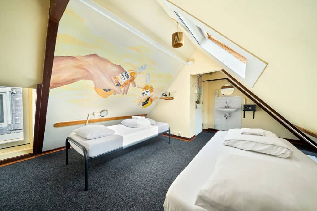 Modern hostel room at Flying Pig Uptown with colourful wall art and comfortable beds.