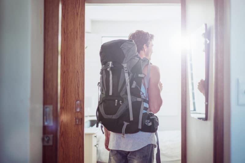 Young man with backpack entering Mitte Hostel in Berlin, bright natural light.