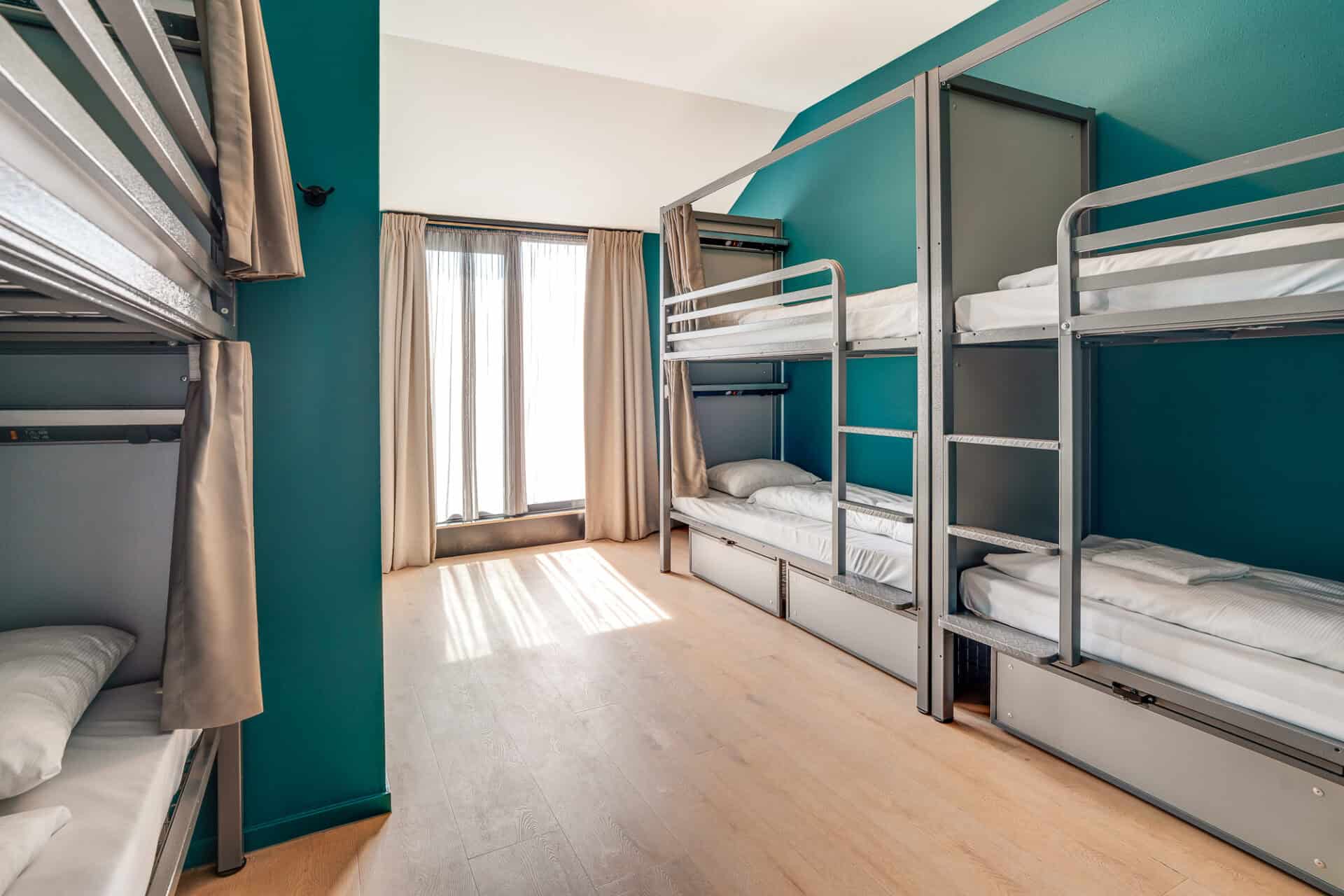 Bright hostel dormitory with bunk beds and natural light.