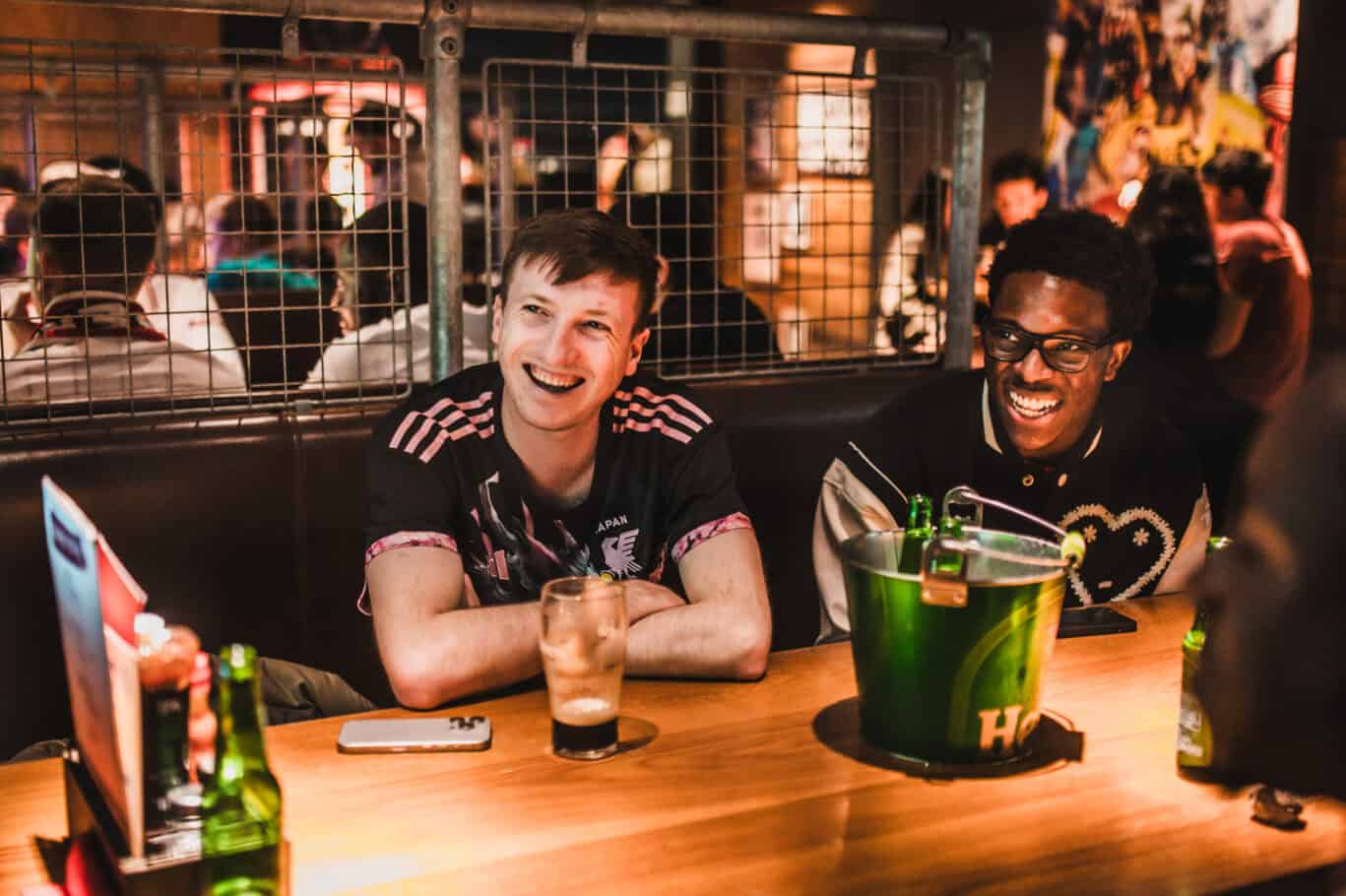 Bright, lively hostel bar with smiling guests enjoying drinks and socialising.