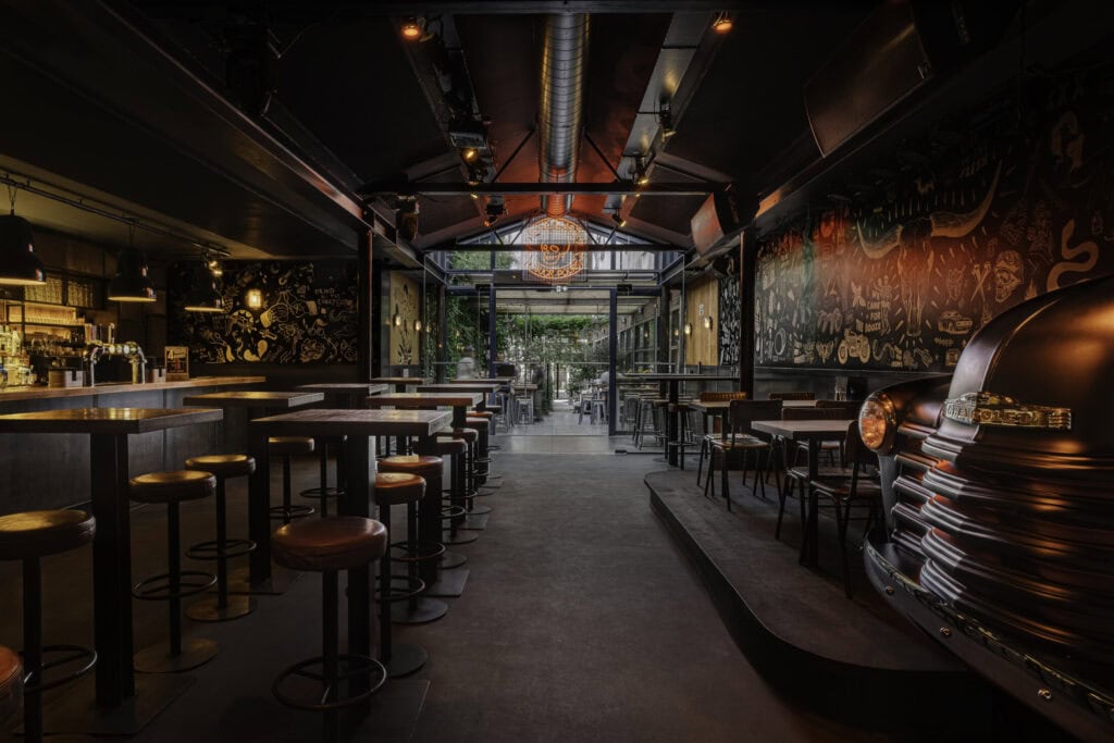 Brightly lit, modern bar with colourful murals and seating area.
