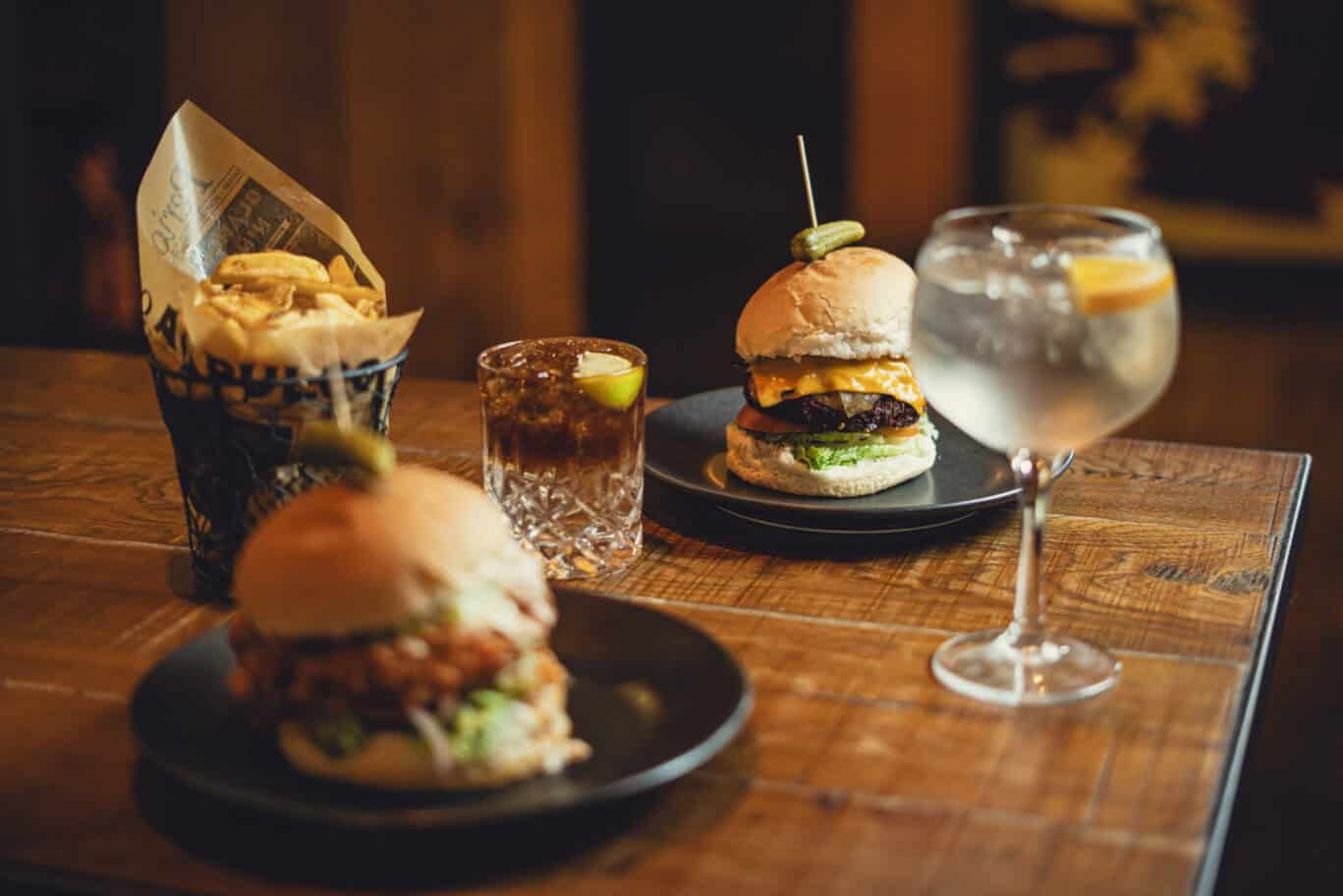 Delicious burgers with fresh ingredients served with refreshing beverages in a cozy setting.