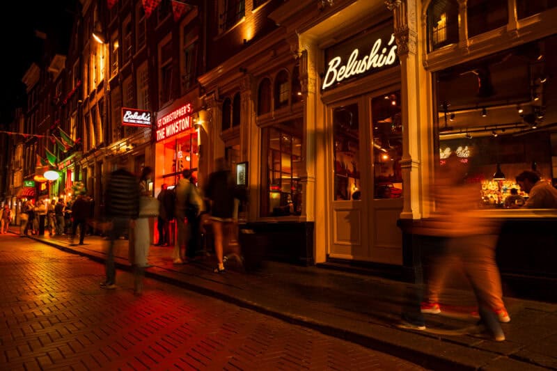 Exterior view of Winston Hostel in Amsterdam at night with lively street scene.