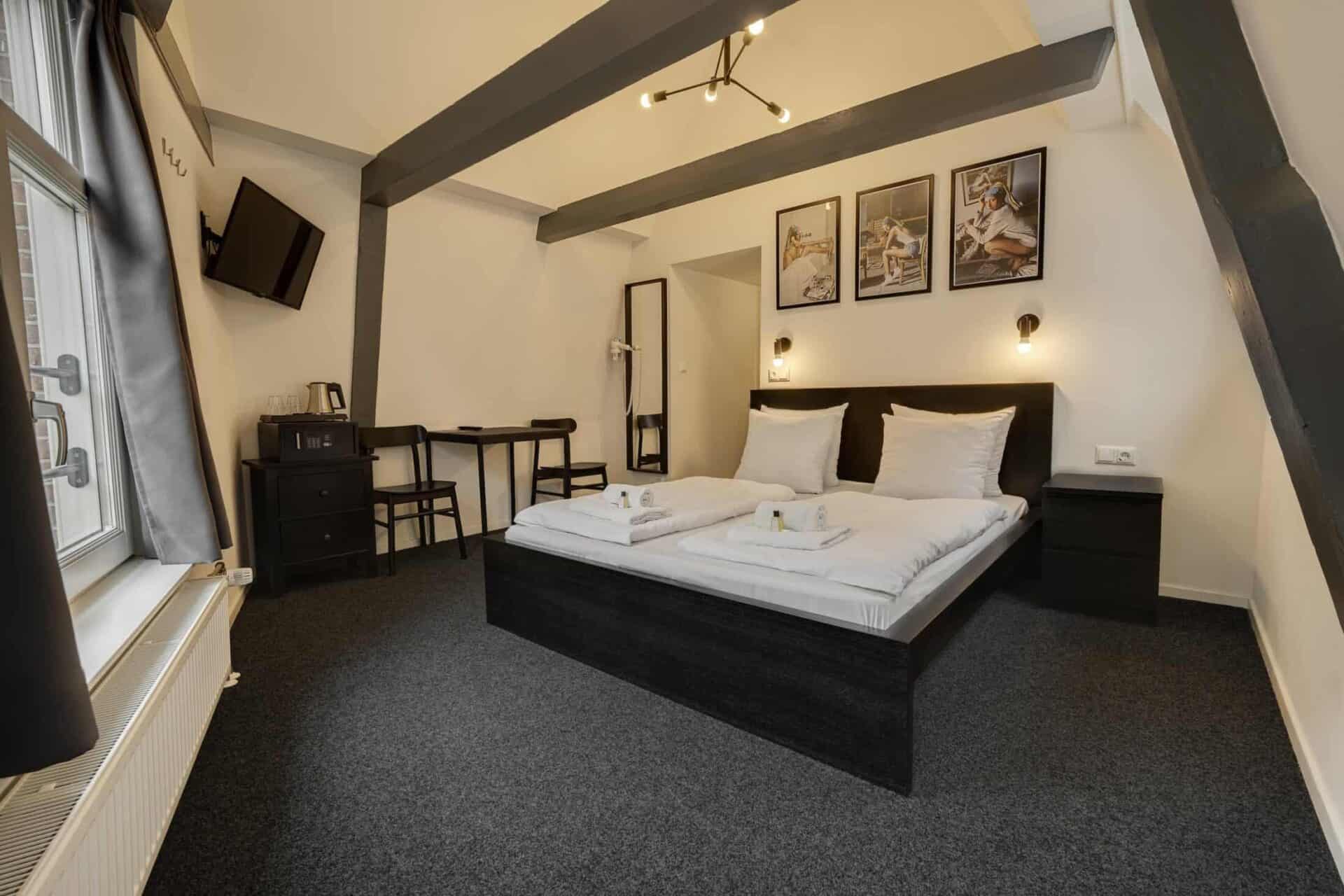 Comfortable double bed in a stylish hotel room at St Christopher’s Amsterdam, featuring modern decor.