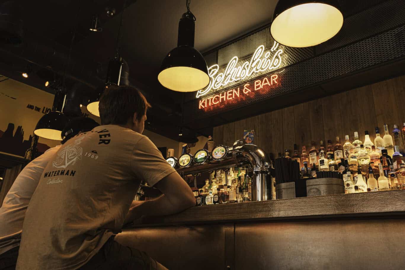 Modern bar at Winston Hostel Amsterdam with warm lighting and a variety of spirits.