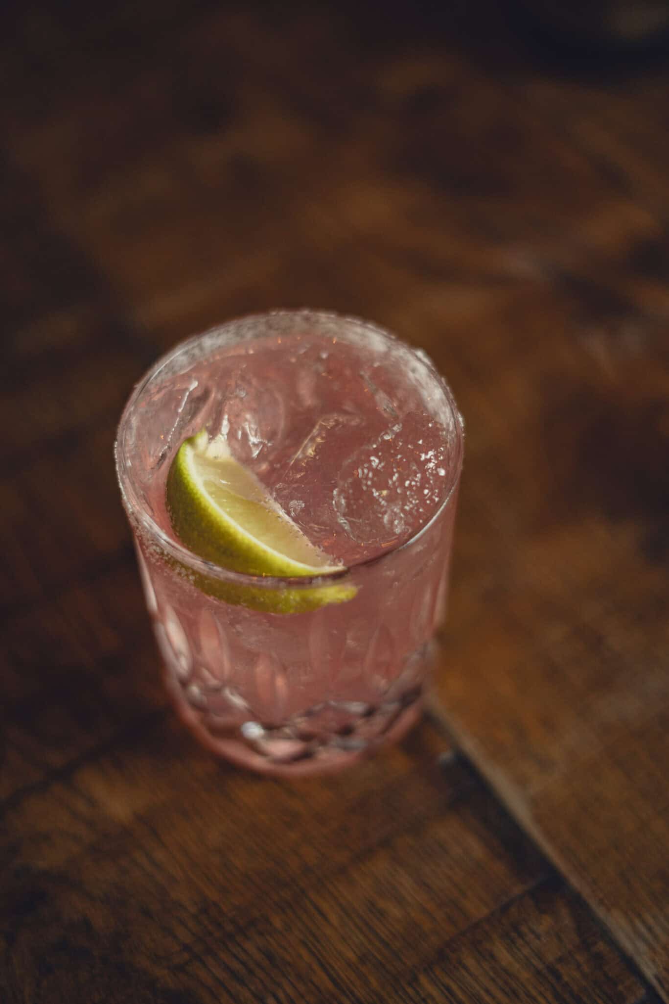 Glass of lime cocktail with ice on a wooden table at Winston Hostel.
