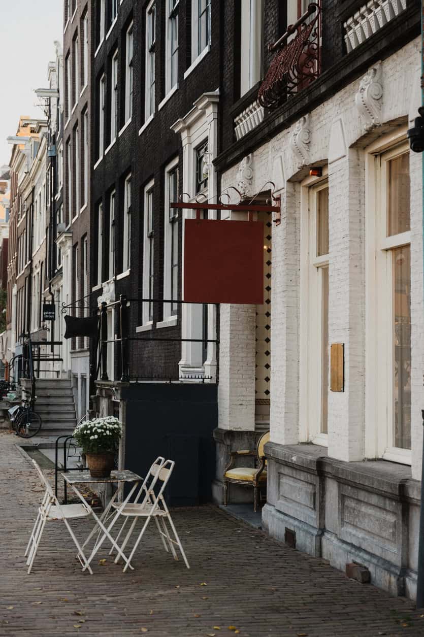 Winston Hostel exterior in Amsterdam with outdoor seating area and historic building facade.
