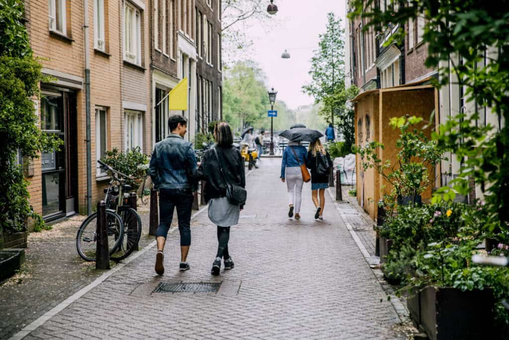 People walking on a cobbled street outside Winston Hostel in Amsterdam.