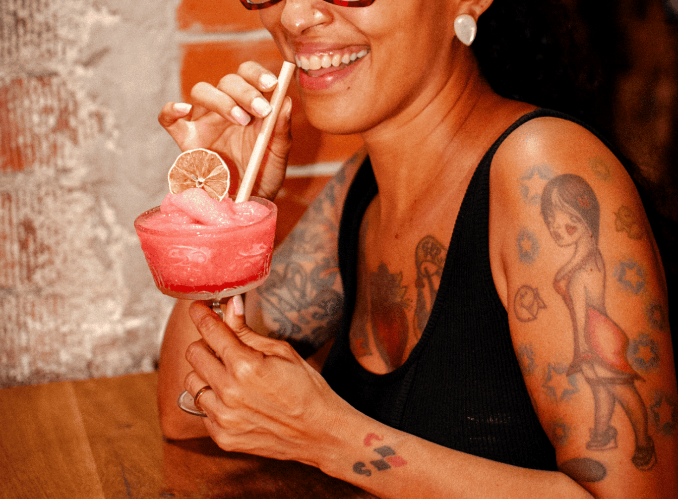 Vibrant woman enjoying a colourful cocktail at St Christopher’s Barcelona hostel.