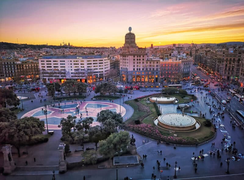 Las Ramblas, Barcelona cityscape at sunset with historic buildings and lively square.