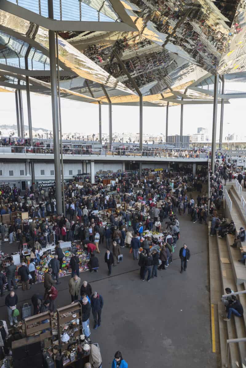 Crowded Barcelona cruise terminal with visitors and modern canopy structure.