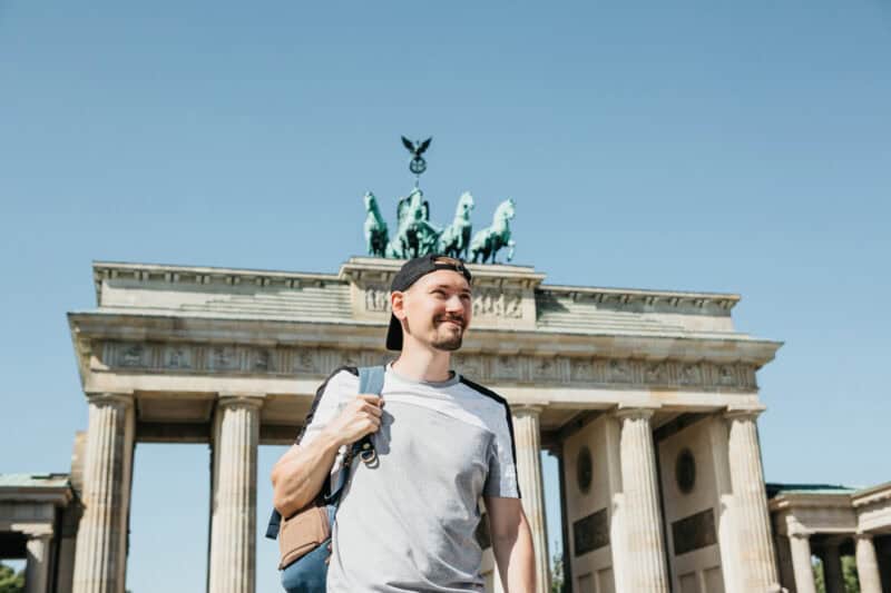 Brandenburg Gate in Berlin with a smiling tourist, a popular travel destination in Germany.
