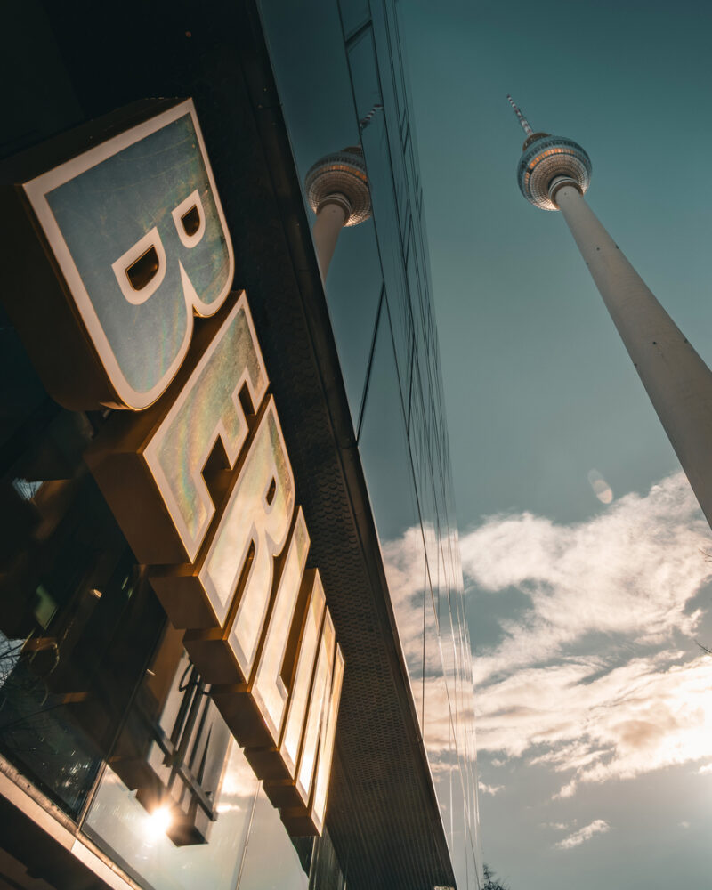 Berlin Sign and Fernsehturm TV Tower Reflected in Glass Facade, Low Angle View at Alexanderplatz