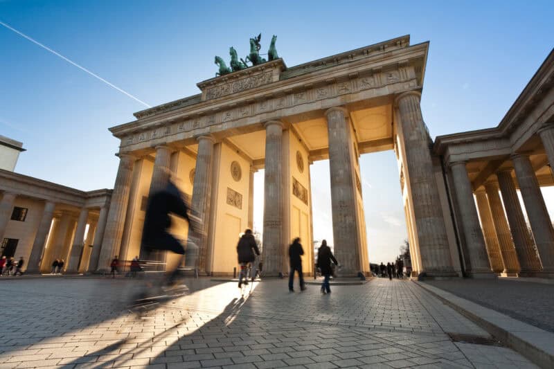 Berlin Brandenburg Gate at sunset with visitors, historic monument in Mitte, Berlin.
