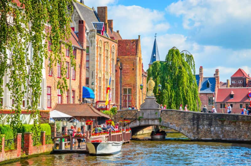 A canal with historic brick buildings and a stone bridge in a European city.