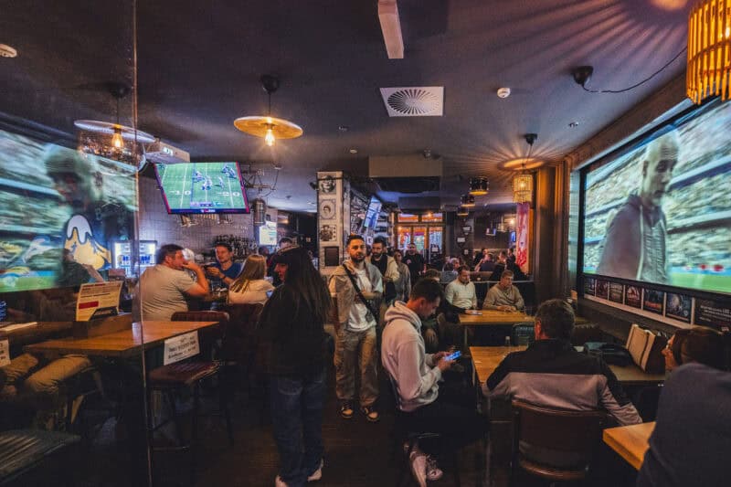 Hostel bar and lounge in Mitte, Berlin, with vibrant atmosphere and large screens for sports viewing.