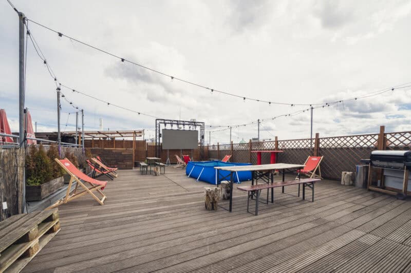 Rooftop terrace with seating, string lights, and a hot tub at St Christopher’s Berlin hostel in Mitt.