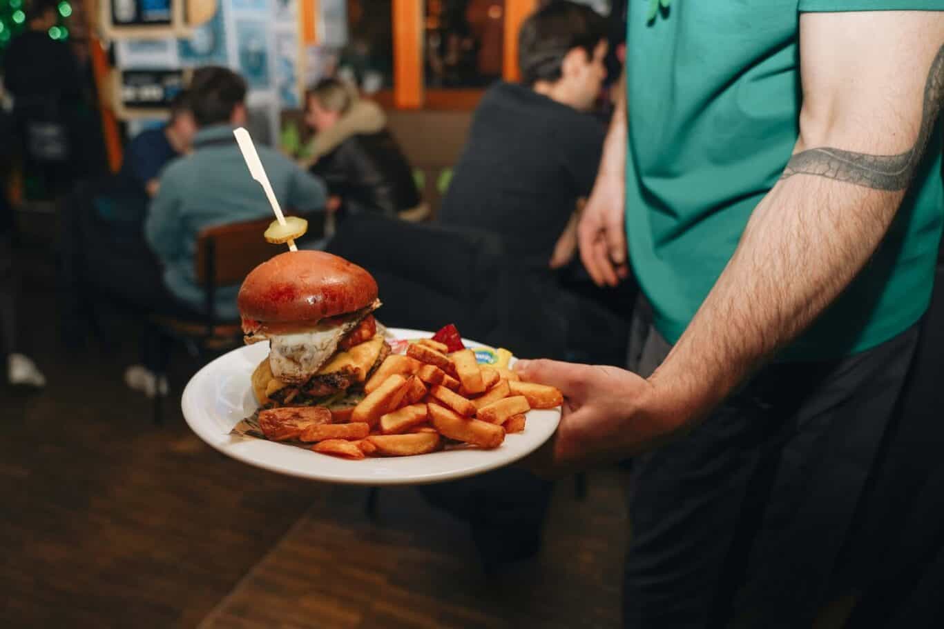 Delicious burger with fries on a plate, served at St Christopher’s Berlin - Mitte hostel.