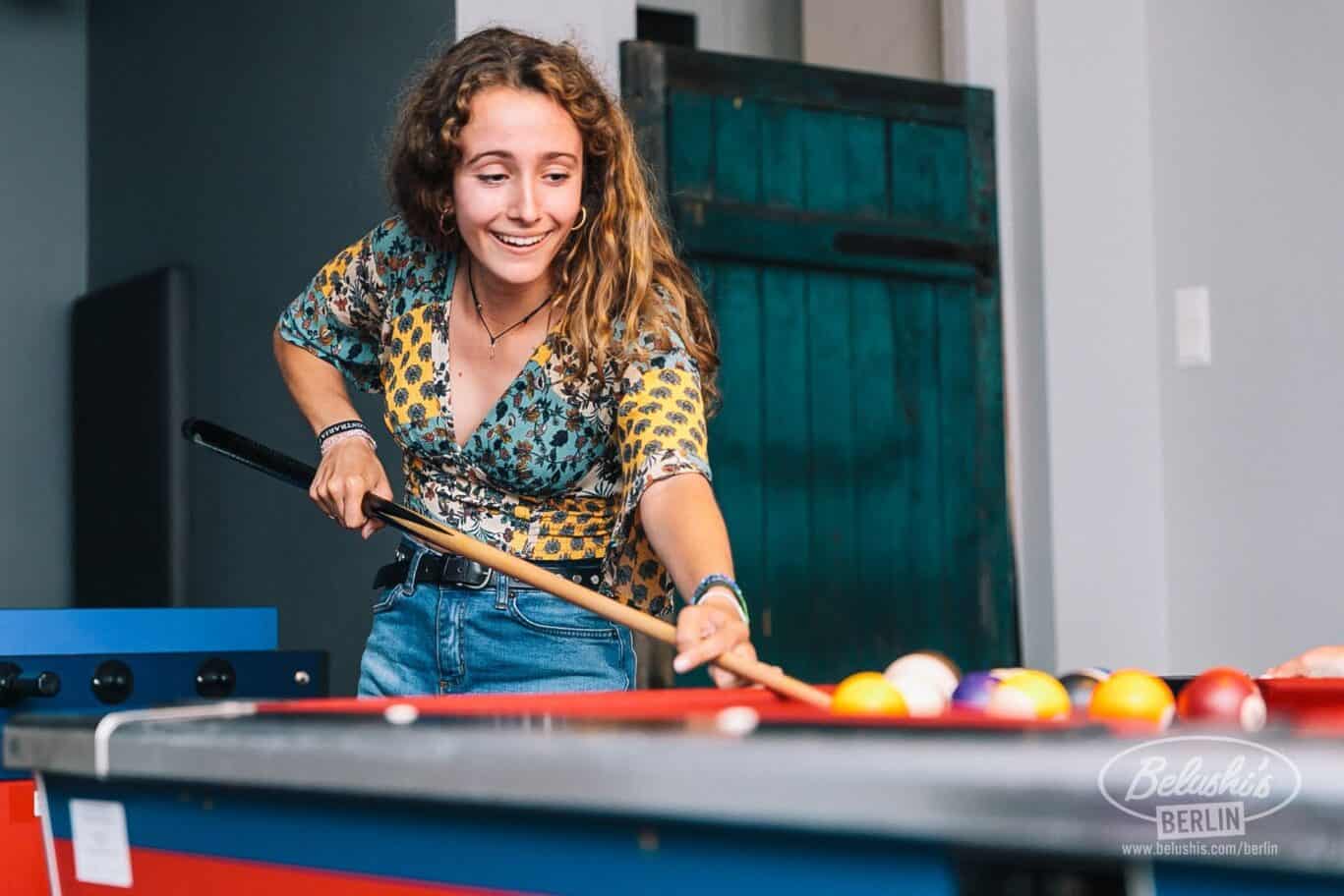 Young woman playing pool at St Christopher’s Berlin - Mitte hostel.