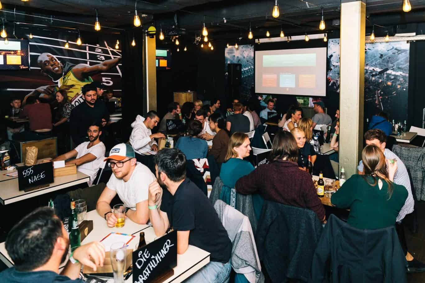 Vibrant social area at Mitte Hostel, St Christopher’s Berlin with guests enjoying drinks and event.