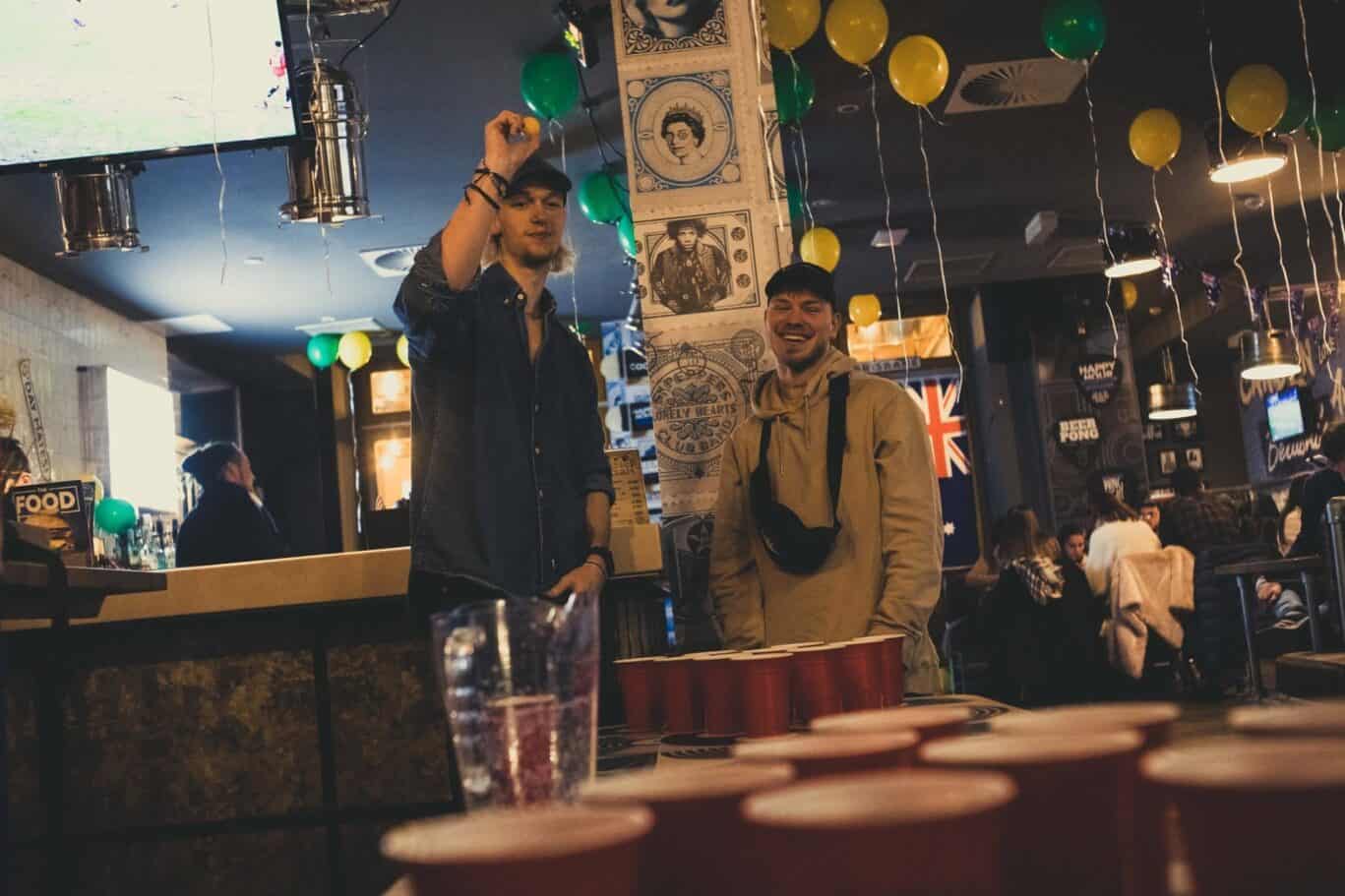 Two young men enjoying drinks at a lively bar in Berlin Mitte.