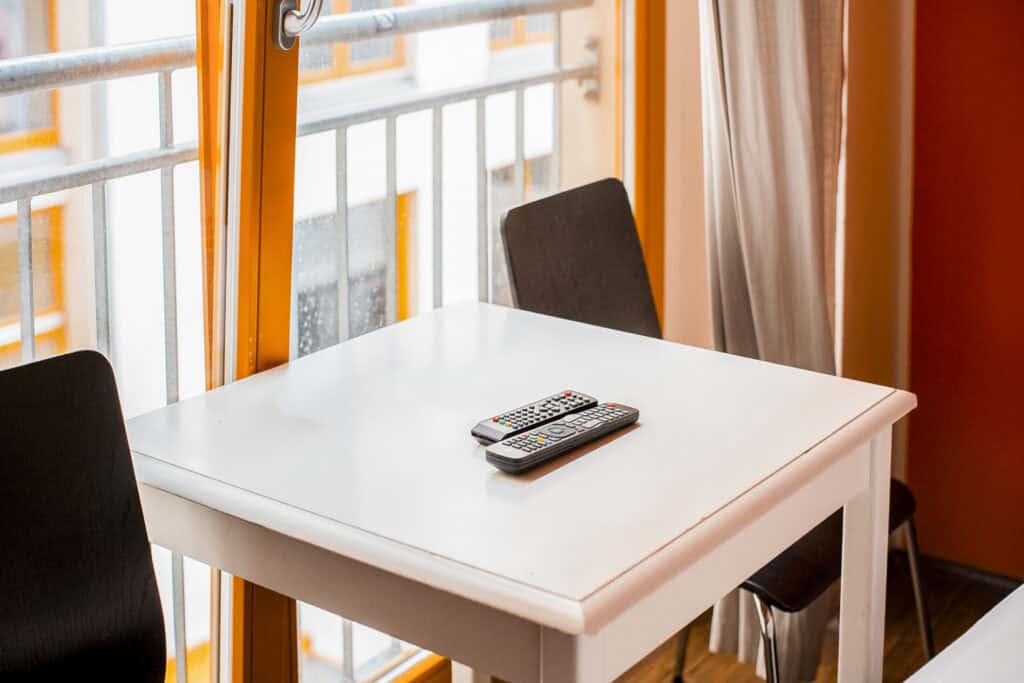 Hostel room with white table, black chairs, and large windows in Berlin Mitte.