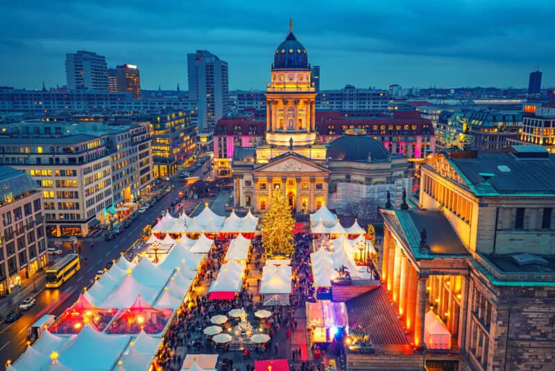 Night view of Mitte Hostel Berlin with festive market tents and historic cityscape.