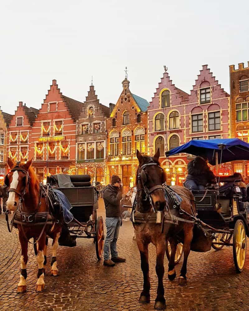 Brightly coloured historic buildings in Berlin's Mitte district with horse-drawn carriages.