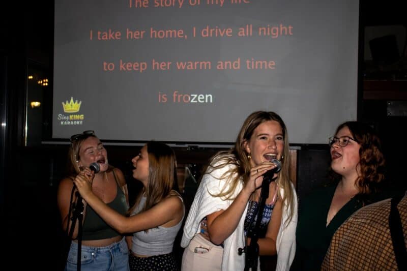 Group of young women singing karaoke at St Christopher’s Bruges hostel.