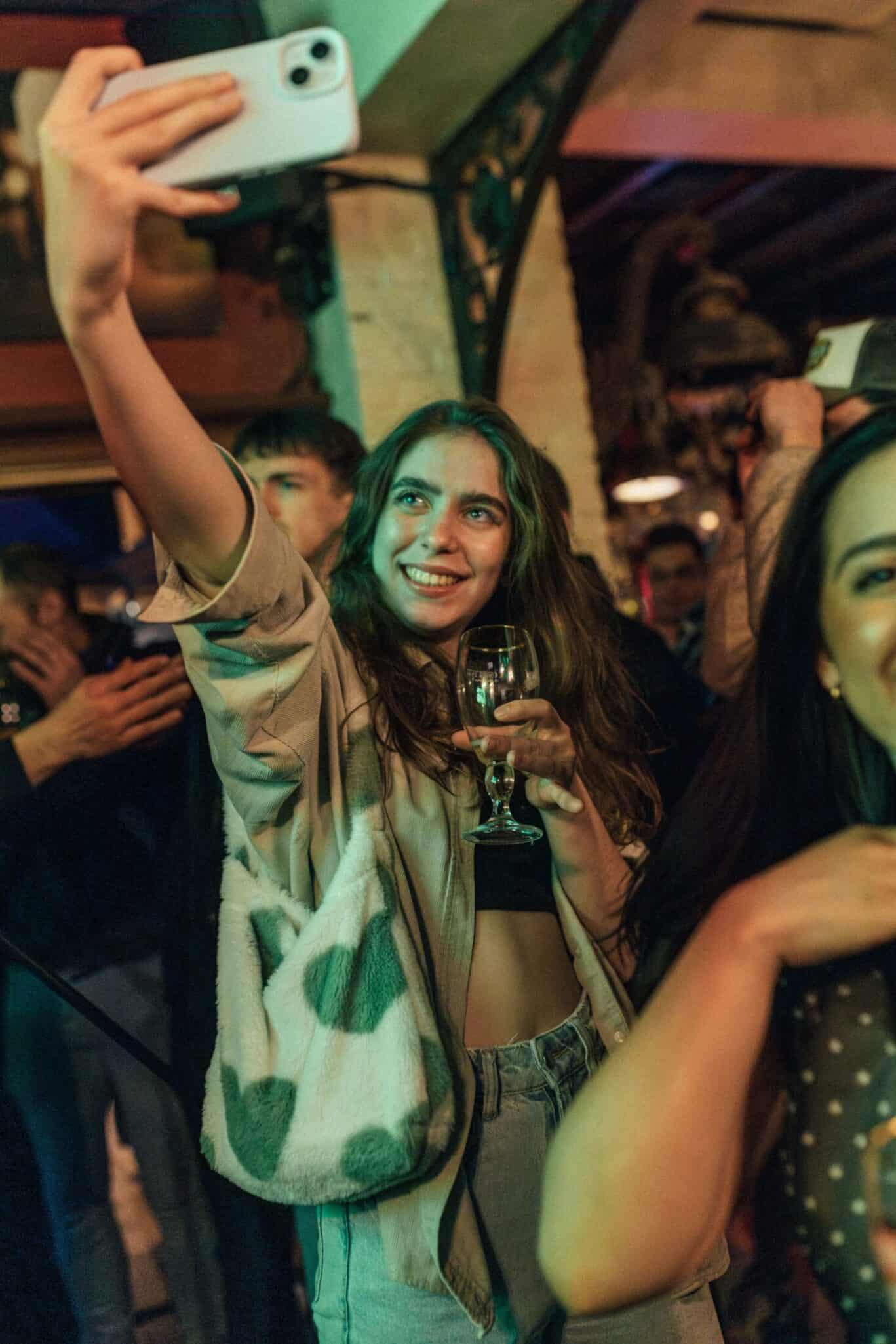 Young woman taking a selfie at a lively social event in Bruges.