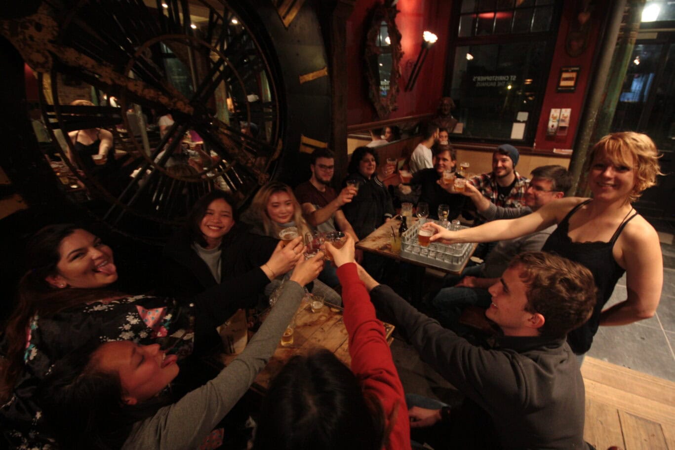 Group of friends sharing a toast at a lively Bruges restaurant.