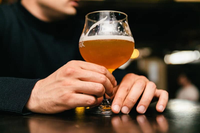 Person holding a glass of beer at St Christopher’s Bruges hostel bar.