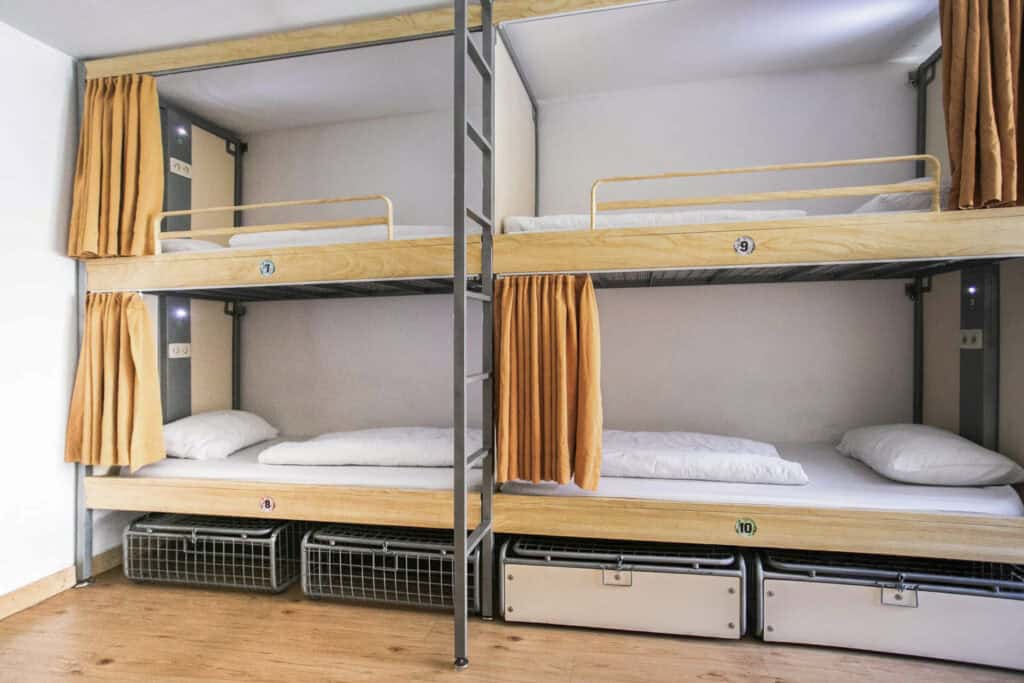 Bunk beds with privacy curtains and storage baskets at St Christopher’s Bruges - The Bauhaus.