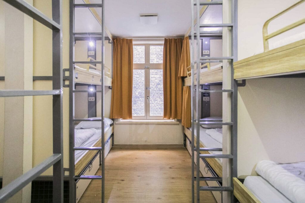 Dormitory room with metal bunk beds and large window at St Christopher’s Bruges - The Bauhaus.