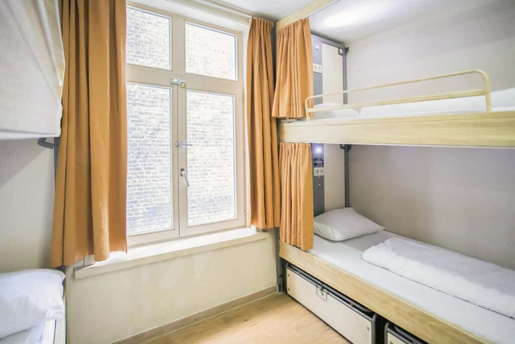 Bright dorm room with bunk beds and large window in St Christopher’s Bruges hostel.
