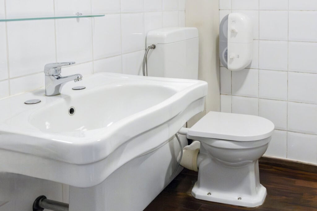 Accessible bathroom with white sink and toilet at St Christopher’s Bruges hostel.
