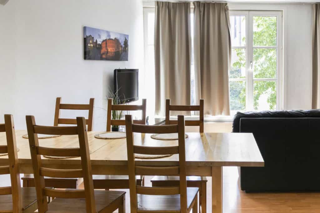 Modern dining area with wooden table and chairs at St Christopher’s Bruges - The Bauhaus hostel.