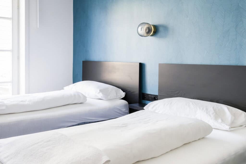Modern hostel room with twin beds and colourful wall decor.