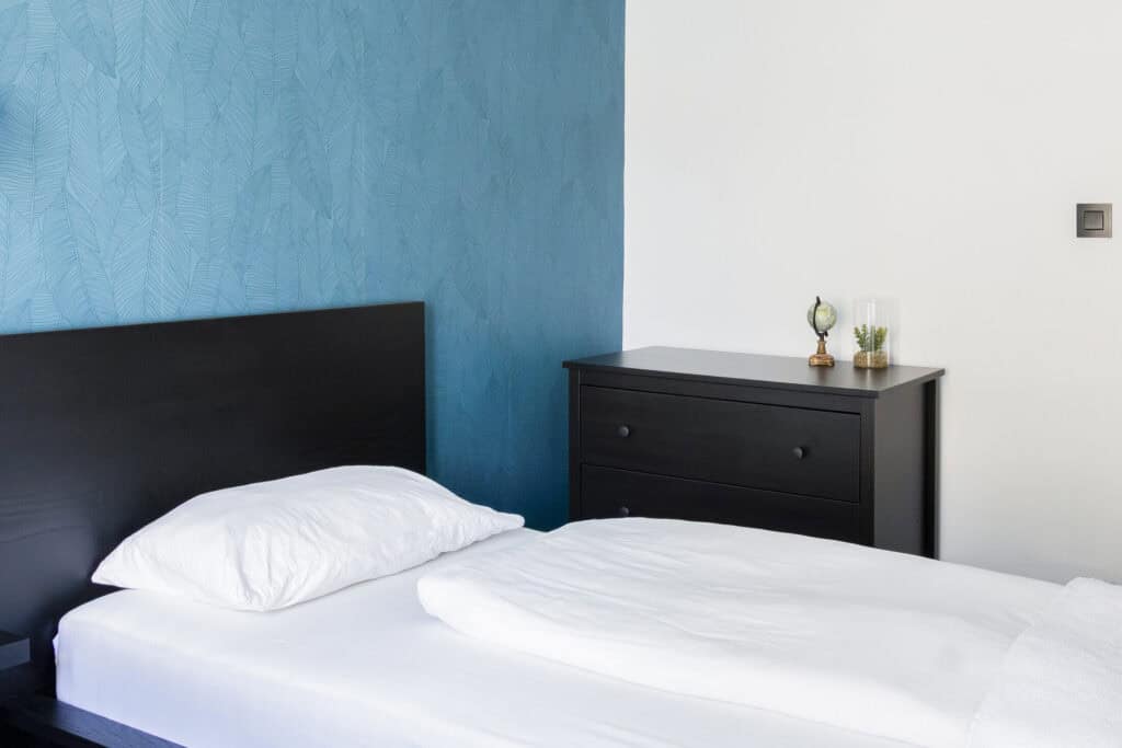 Modern hostel bedroom with minimalist decor and a black bed frame.