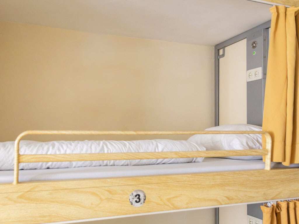 Hostel bunk bed with safety rail in a bright, modern dorm room at St Christopher’s Bruges - The Bauh.