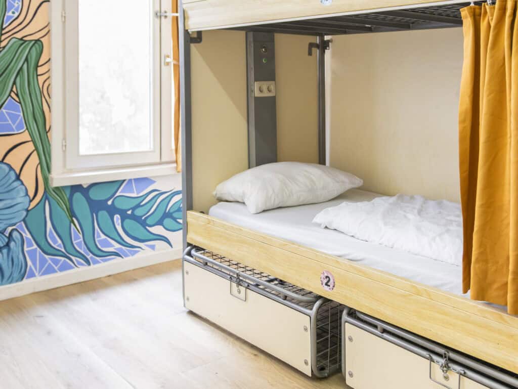 Bunk bed in Bauhaus-themed hostel room at St Christopher’s Bruges, featuring colourful wall art and.