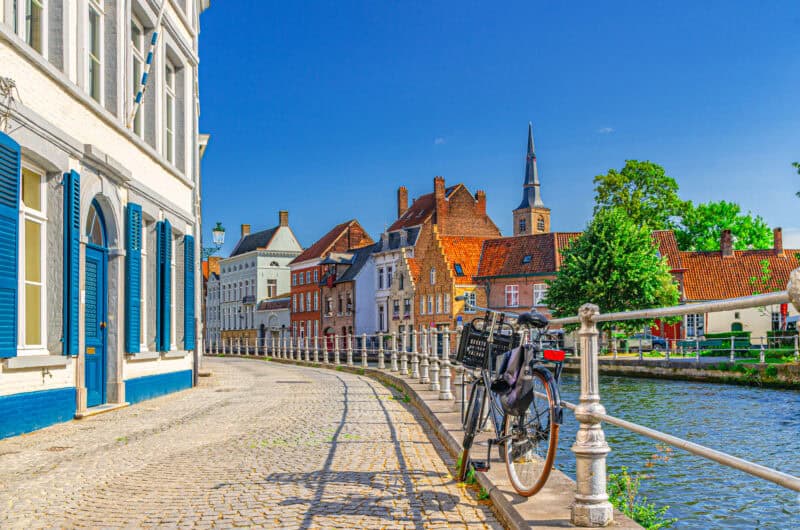 Scenic view of Bruges canal with historic buildings and a bicycle in front of the Bauhaus Hostel.