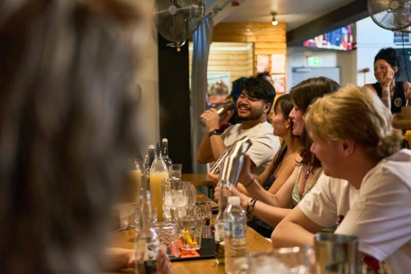 Group of young adults enjoying drinks at a lively bar in St Christopher’s Edinburgh hostel.