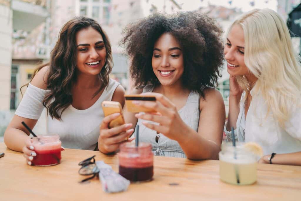Vibrant group of diverse friends smiling and taking selfies at an outdoor café in Edinburgh.