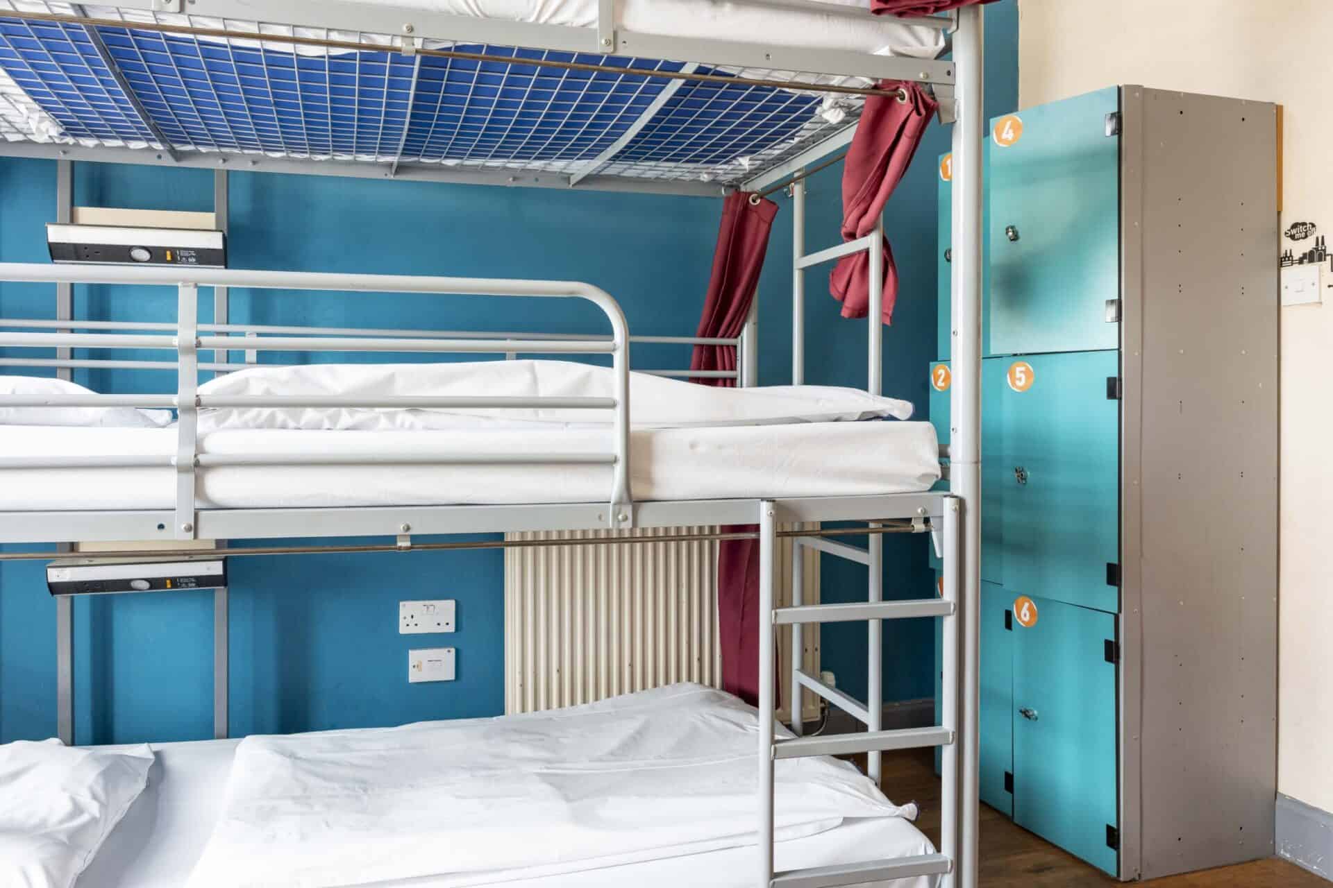 Bunk beds in a hostel dorm room with lockers and vibrant decor.