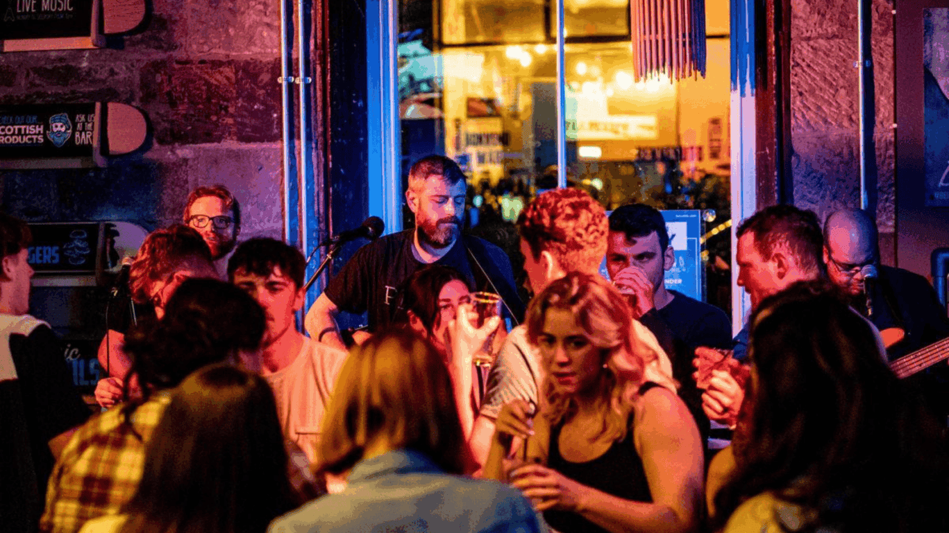Vibrant nightlife scene at St Christopher’s Edinburgh hostel bar with young travellers socialising.